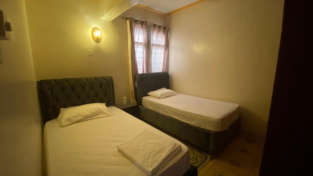 a small room with two beds and a window at Al Maaroof Appartment in Mombasa