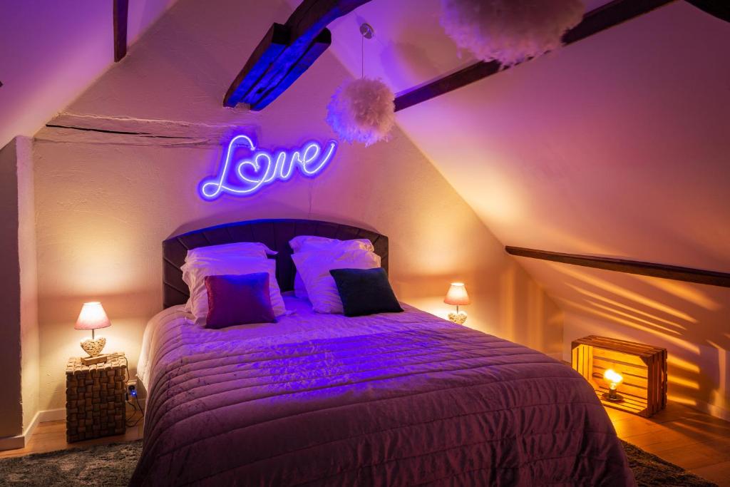 ein Schlafzimmer mit einem Bett mit einem Liebesschild an der Wand in der Unterkunft Pour Toi et Moi - Loveroom in Saint-Martin-des-Bois