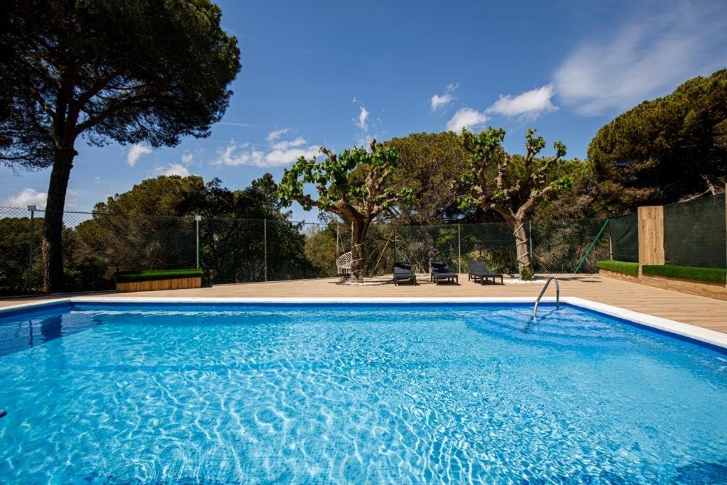 una grande piscina blu con alberi sullo sfondo di Maravillosa casa con piscina grande y bosque a Tordera