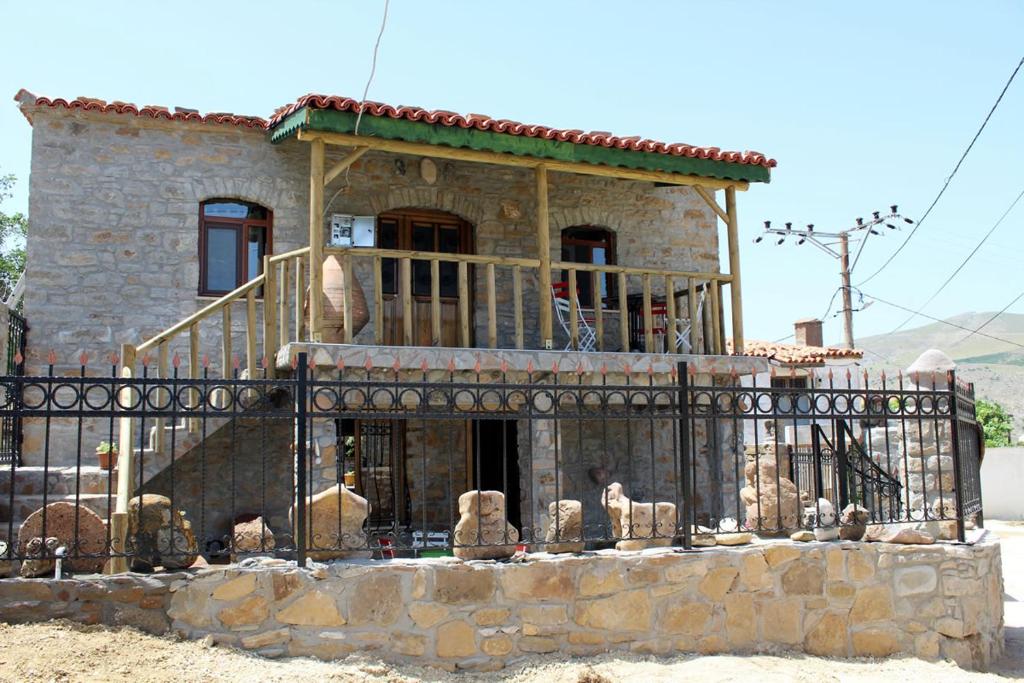 une maison en pierre avec une clôture devant elle dans l'établissement KALYOPİ TAŞ BUTİK OTEL, à Gokceada Town