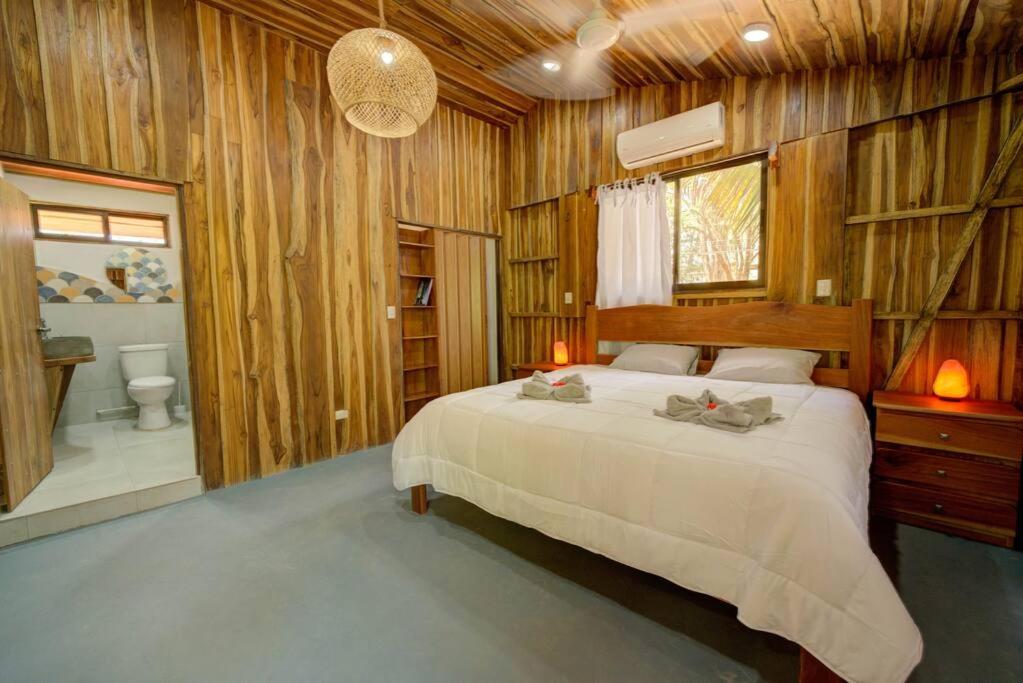 a bedroom with a bed and a bathroom with a toilet at Sámara Tarantela Houses, Casa Bambú in Sámara