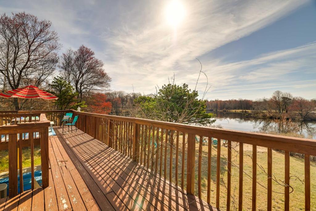 ein Holzdeck mit Sonnenschirm und Wasserfläche in der Unterkunft Dock and Fire Pit Lakefront Poconos Retreat! in Long Pond