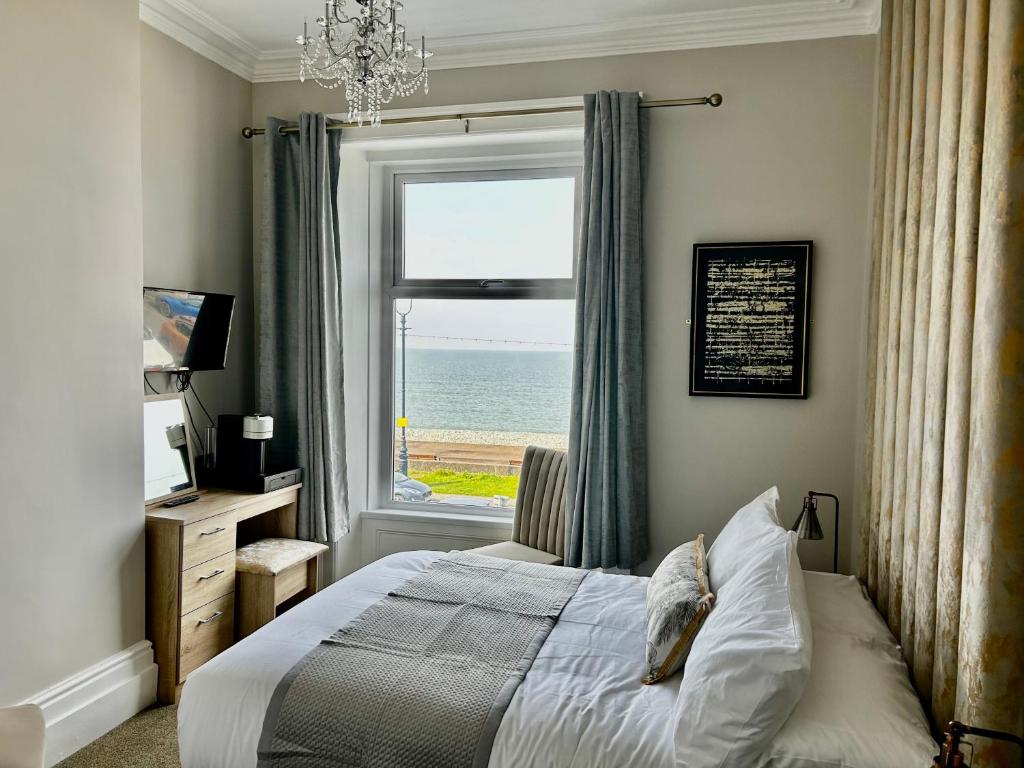 a bedroom with a bed and a window with the ocean at Hotel No5 Beach front with Free Private Car Park in Llandudno