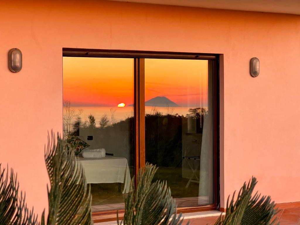 Drapia的住宿－GREEN APARTMENT in VILLA ANGISI，透过粉红色房子的窗户看到的日落