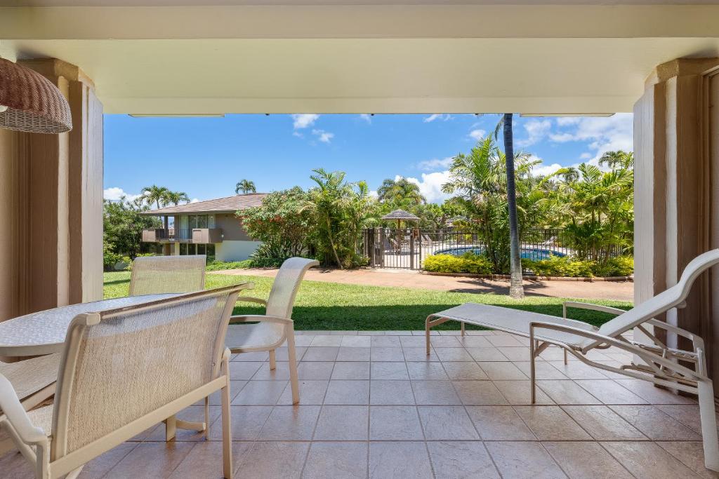 a patio with a table and chairs and a view of a yard at Maui Eldorado E106 in Kahana