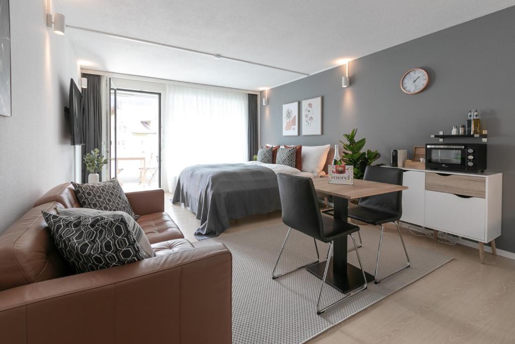 Sala de estar con cama, sofá y mesa en Spirit Apartments - Studio #3 - Balkon - Parkplatz, en Engelberg