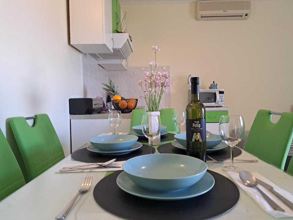 a table with plates and a bottle of wine on it at Apartment Penić in Kaštela