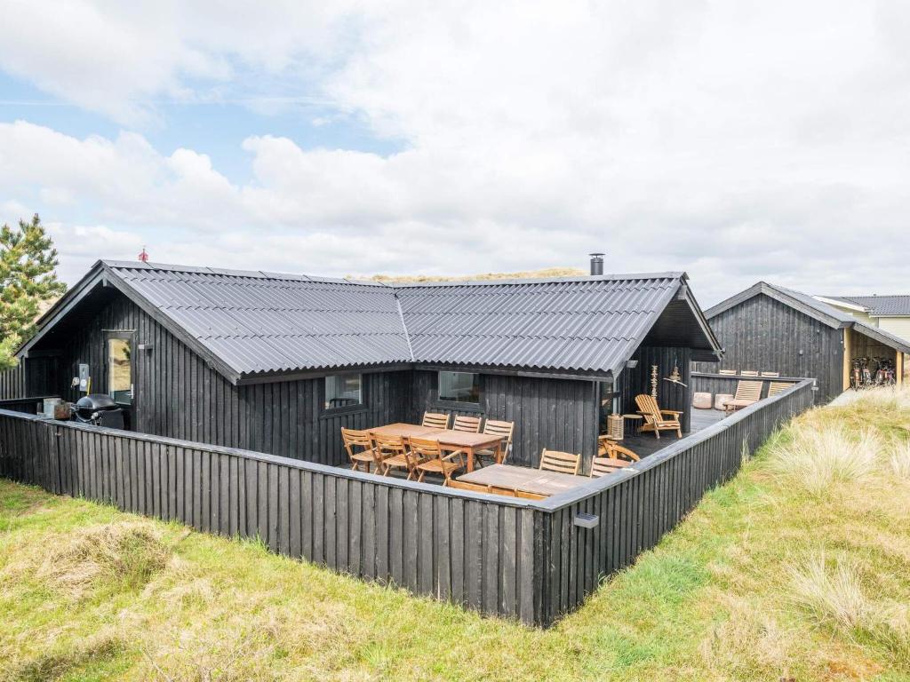 una casa nera con terrazza in legno e tavolo di Holiday home Fanø CL a Fanø