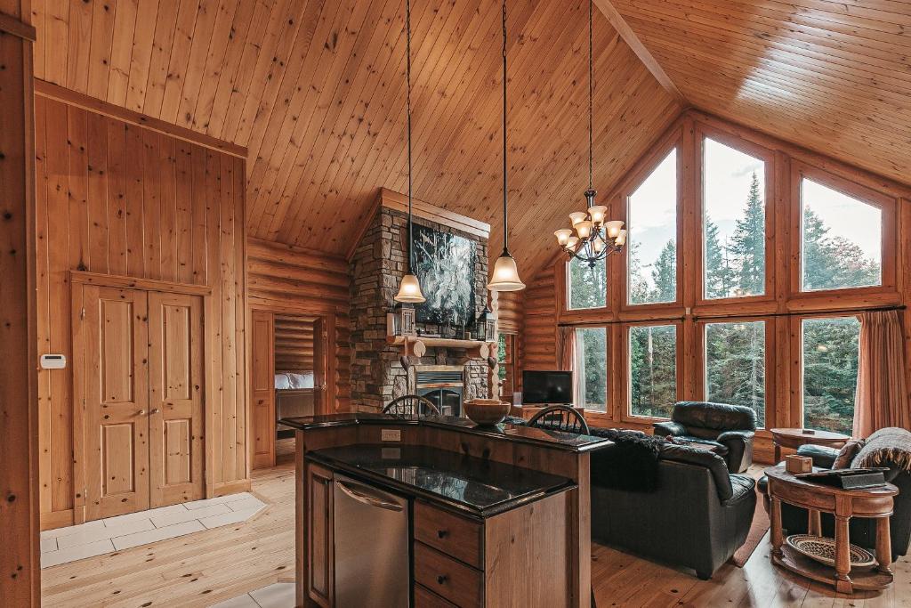 un salon avec des murs en bois et une cuisine avec une cuisinière dans l'établissement 5-Bedroom Getaway with Sauna, BBQ, and Game Room, à Mille-Isles