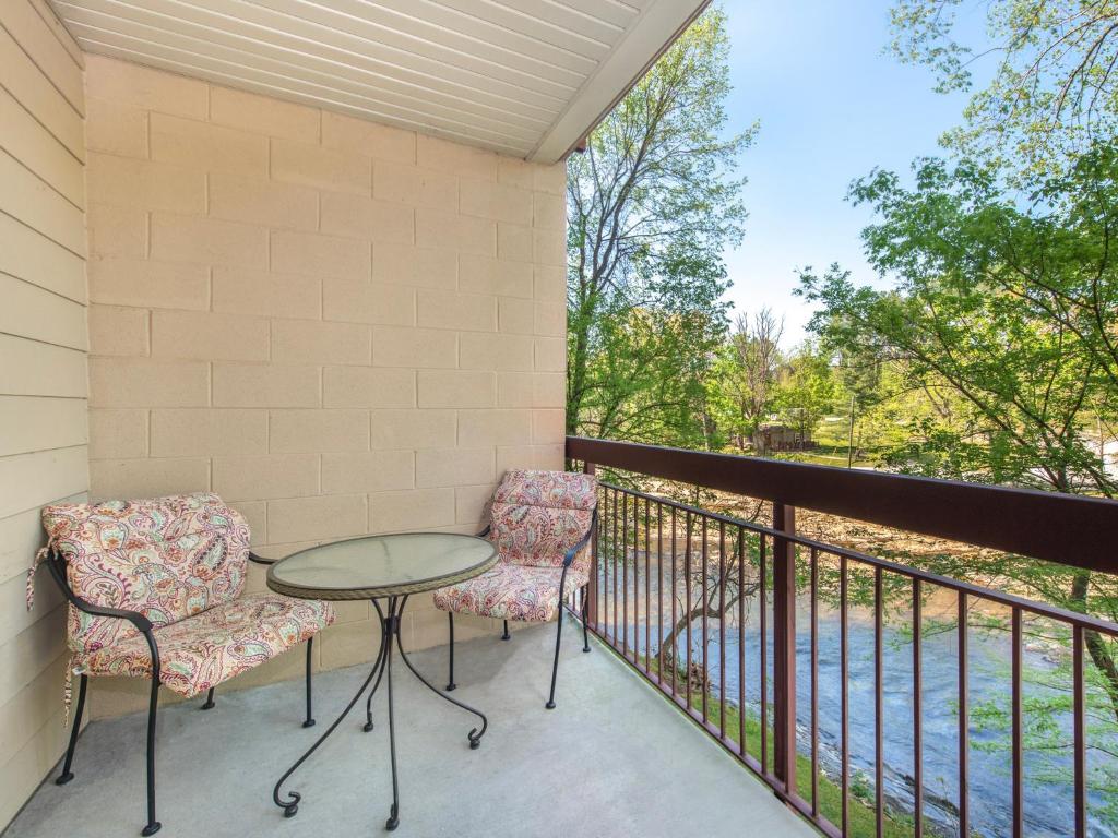 een patio met 2 stoelen en een tafel op een balkon bij Riverside Dream Cedar Lodge 103 in Pigeon Forge