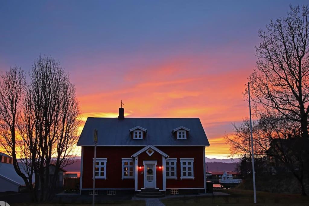 a red house with a sunset in the background at The Foreman house - an authentic town center Villa in Húsavík