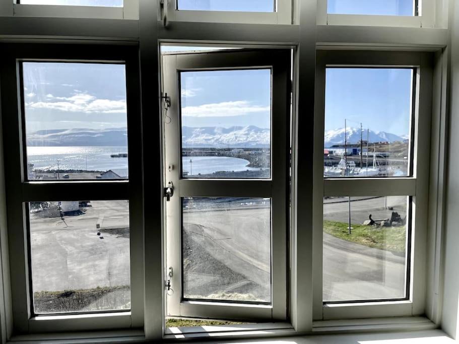 a room with three windows looking out at the water at The Foreman house - an authentic town center Villa in Húsavík