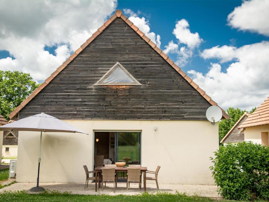 a house with a table and chairs and an umbrella at Le Lac Bleu nr 33 in Lacapelle-Marival