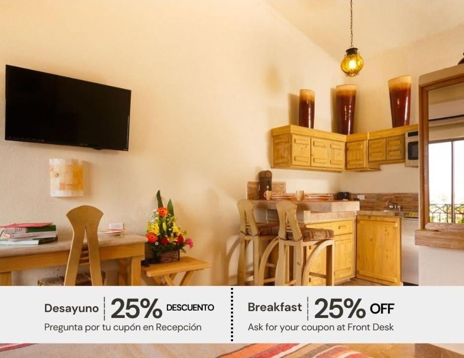 a kitchen with a table and a tv on the wall at Cabo Vista Hotel Adults Only in Cabo San Lucas