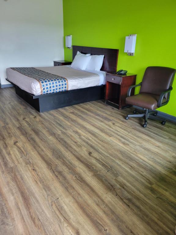 a bedroom with a bed and a desk and a chair at Zainee Inc Budgetel Inn and Suites in Augusta