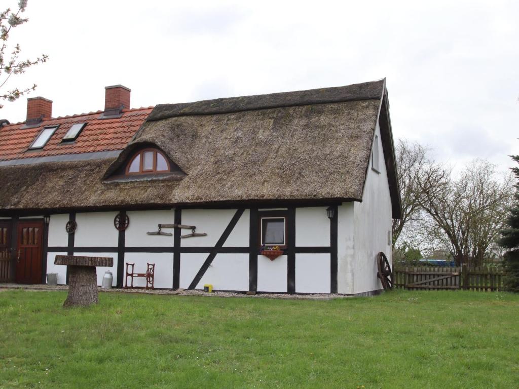 a white and black building with a thatched roof at Thatched roof house in Pogreß with a large plot 