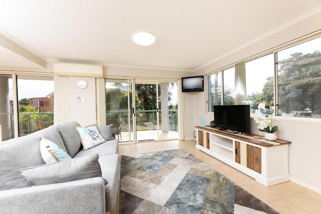een woonkamer met een bank en een flatscreen-tv bij Beachside 2 in Tuncurry