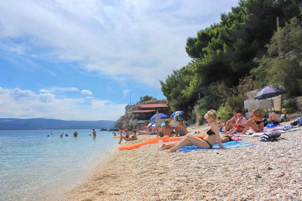 a group of people sitting on a beach at Apartments by the sea Dugi Rat, Omis - 21074 in Dugi Rat
