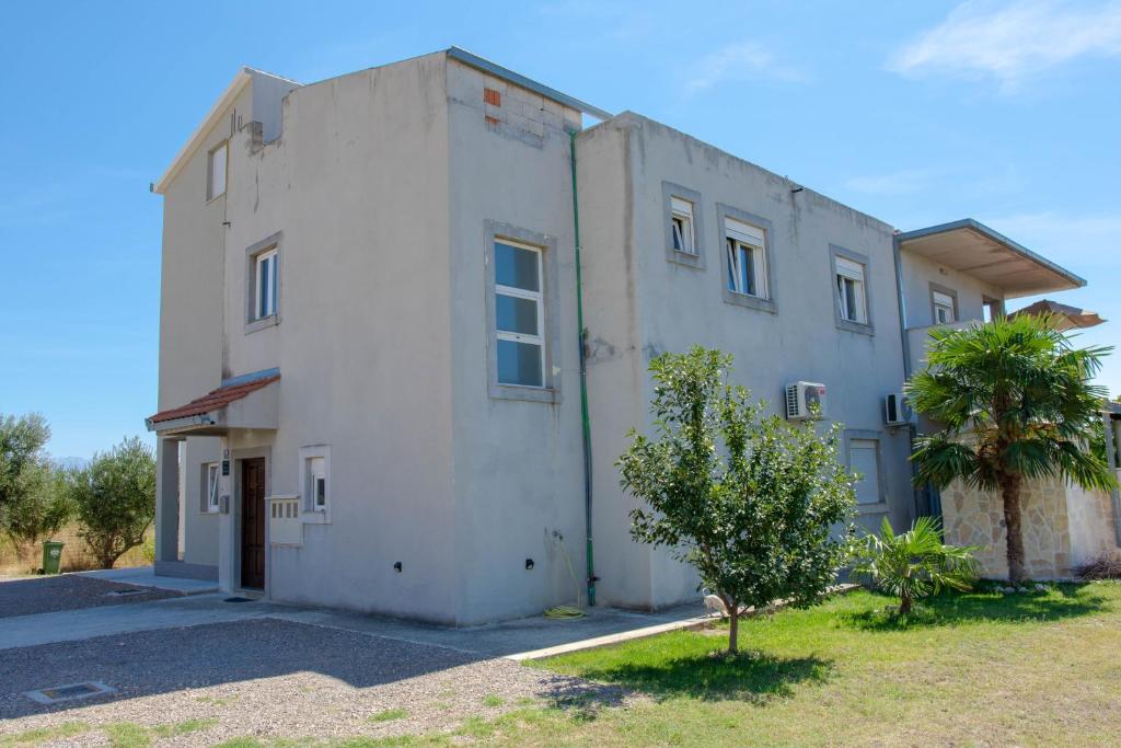 ein weißes Gebäude mit einem Baum davor in der Unterkunft Apartments by the sea Kastel Stafilic, Kastela - 21087 in Kaštela