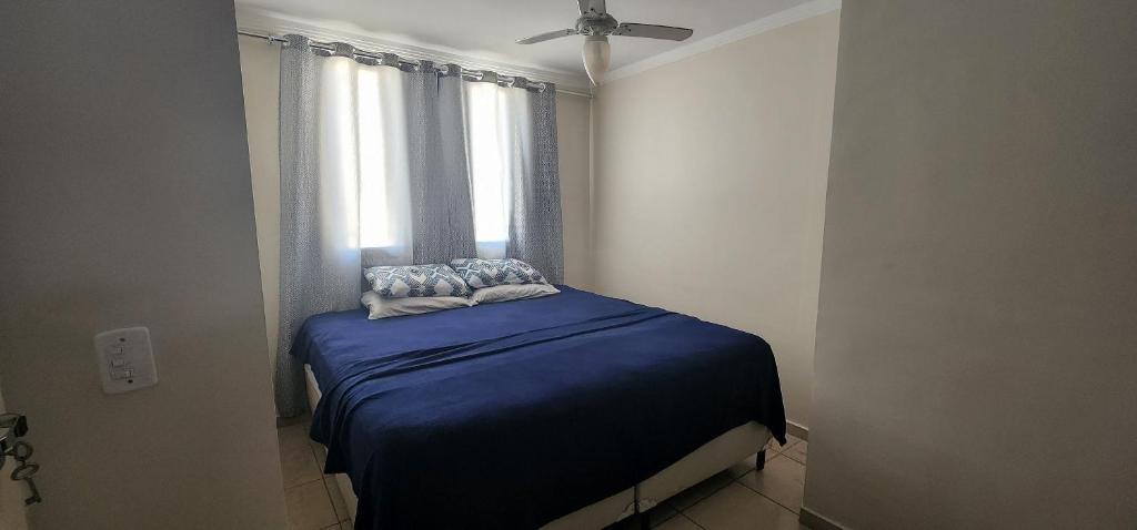 um pequeno quarto com uma cama azul e uma janela em Apartamento - Dois Dormitórios - Todo Equipado em Bauru