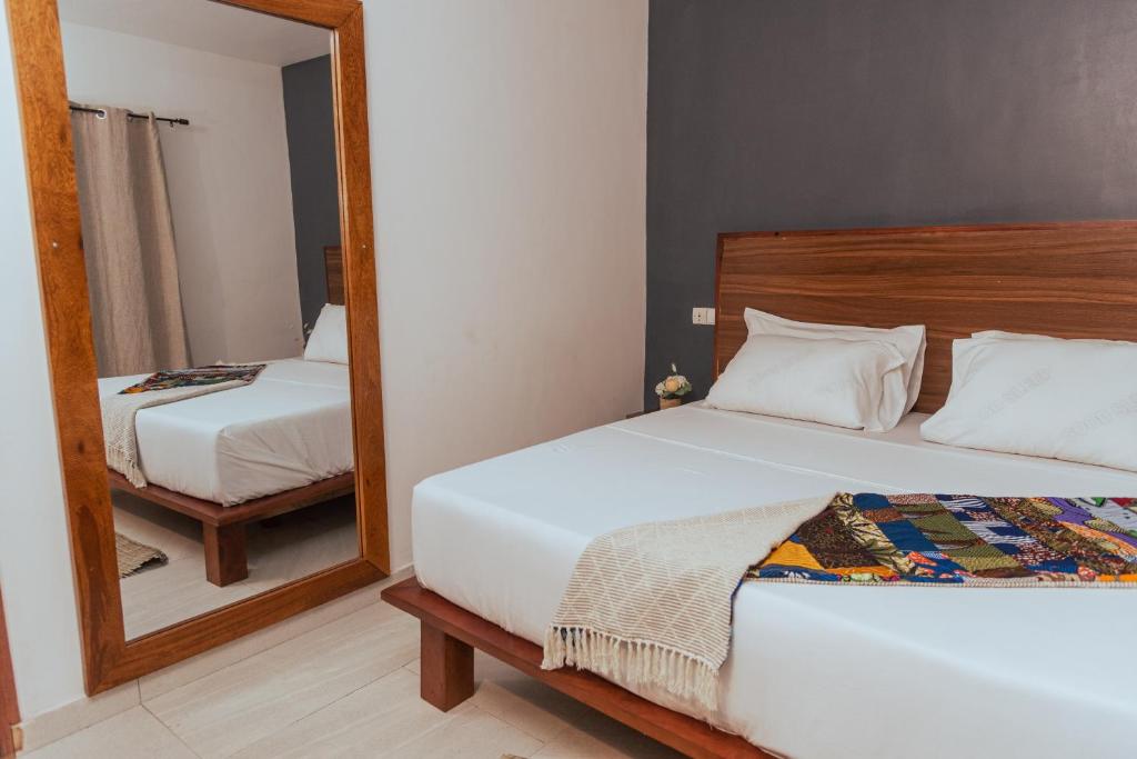 a bedroom with two beds and a mirror at Ahomé Guest house & Lounge in Lomé