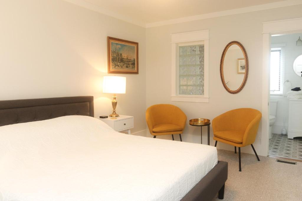 a bedroom with a bed and two chairs and a mirror at Jackson's Falls Country Inn in Milford