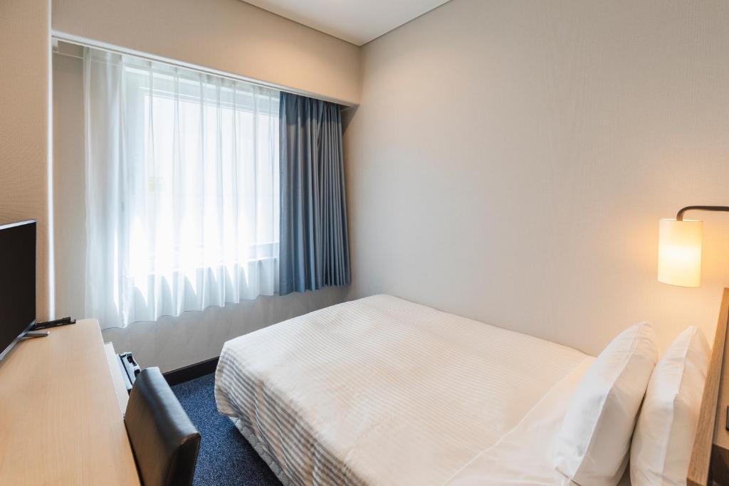 a hotel room with a bed and a window at Sotetsu Fresa Inn Tokyo-Toyocho in Tokyo