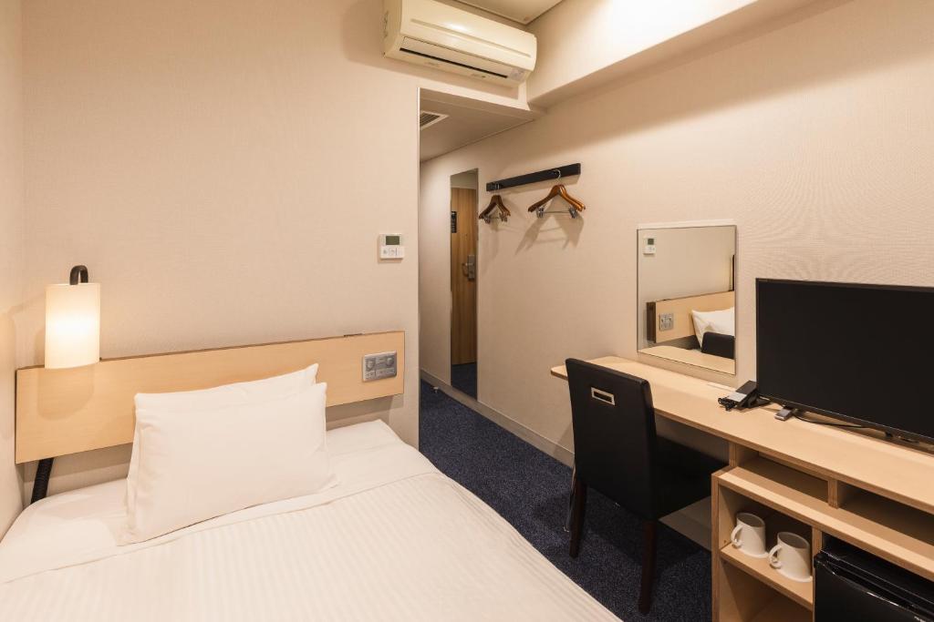 a bedroom with a bed and a desk with a television at Sotetsu Fresa Inn Tokyo-Toyocho in Tokyo