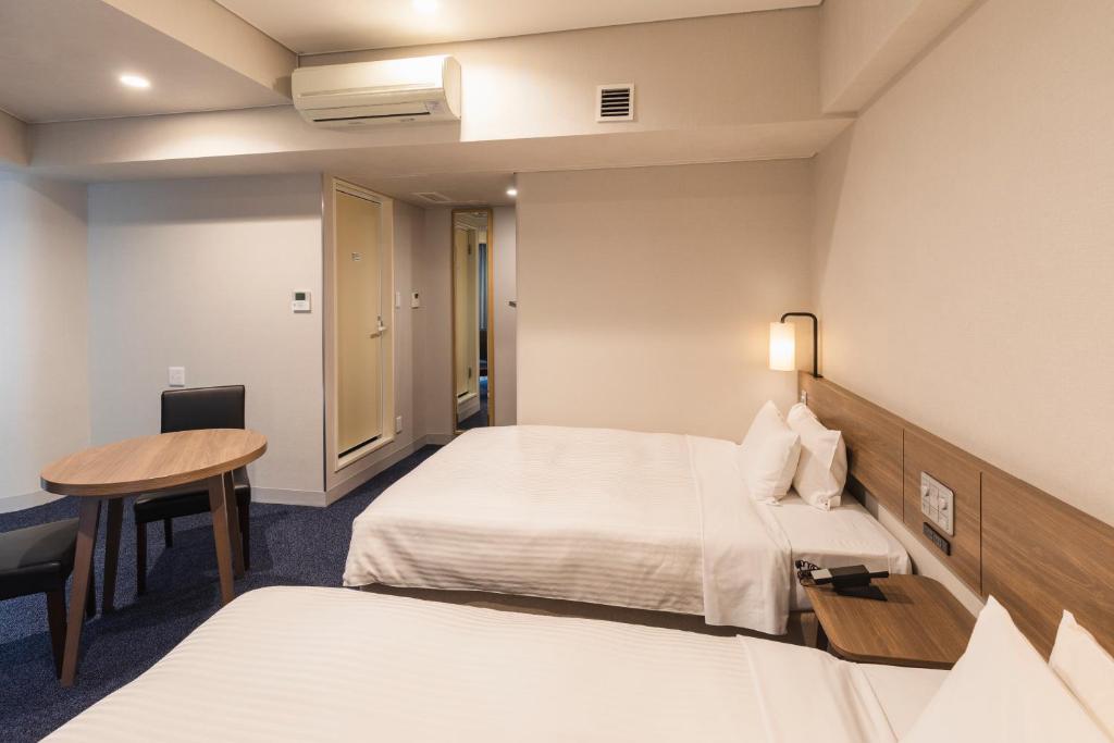 a hotel room with two beds and a table at Sotetsu Fresa Inn Tokyo-Toyocho in Tokyo