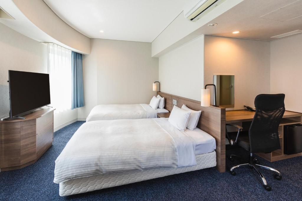 a hotel room with a bed and a desk and a television at Sotetsu Fresa Inn Tokyo-Toyocho in Tokyo