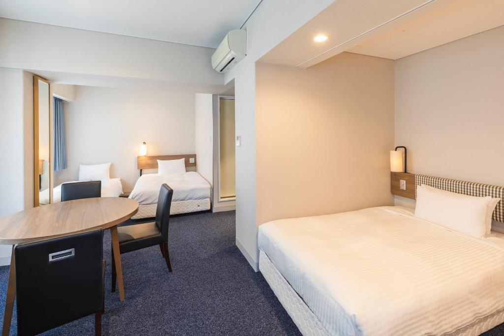 a hotel room with two beds and a table at Sotetsu Fresa Inn Tokyo-Toyocho in Tokyo