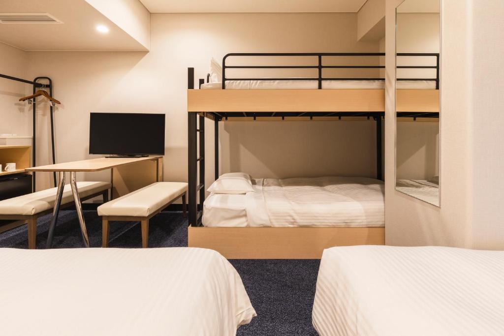a dorm room with two bunk beds and a desk at Sotetsu Fresa Inn Tokyo-Toyocho in Tokyo