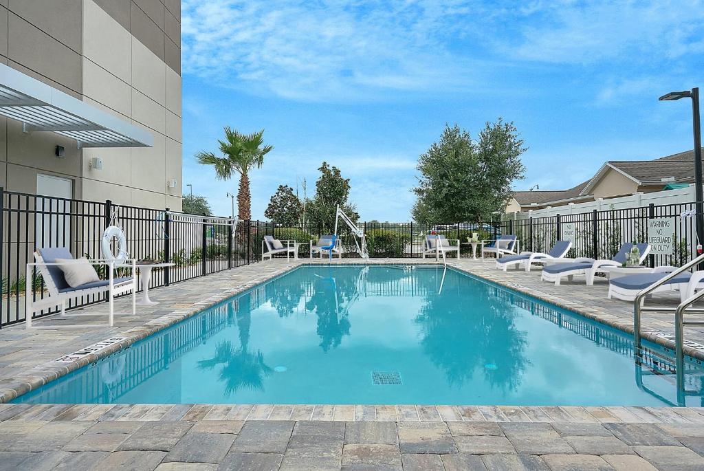 a swimming pool with chairs and a fence at Holiday Inn Express - Jacksonville South Bartram Prk, an IHG Hotel in Jacksonville