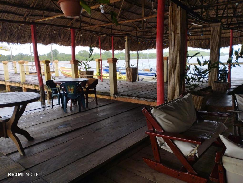 a porch with a couch and tables and chairs at Hotel Little Queen Lobster in Laguna de Perlas