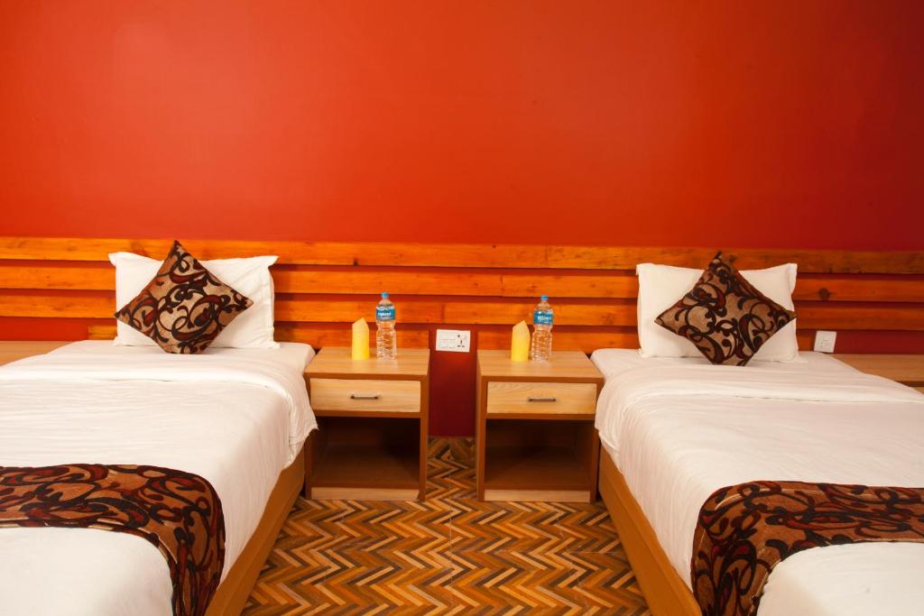 Una habitación con 2 camas y una mesa con botellas. en Sauraha Holiday Home Riverside en Chitwan