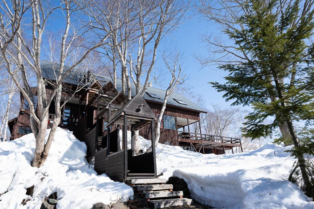 una cabaña de madera en la nieve con un árbol en Niseko HyKrots IKIGAI Village, en Niseko