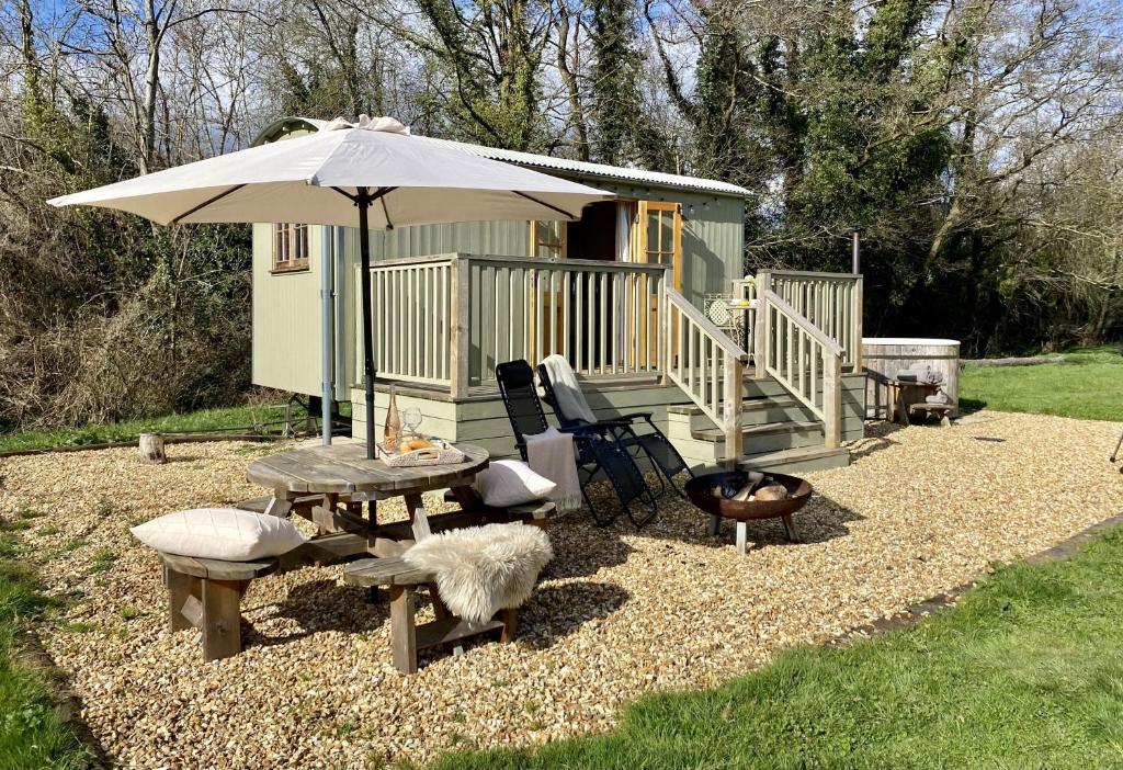 una mesa de picnic y una sombrilla junto a una cabaña en Kingfisher, en Chirk