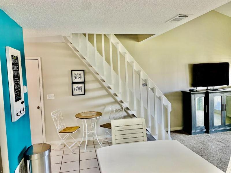 a living room with a staircase and a table and chairs at 10 H Two Bedroom Condo in Destin