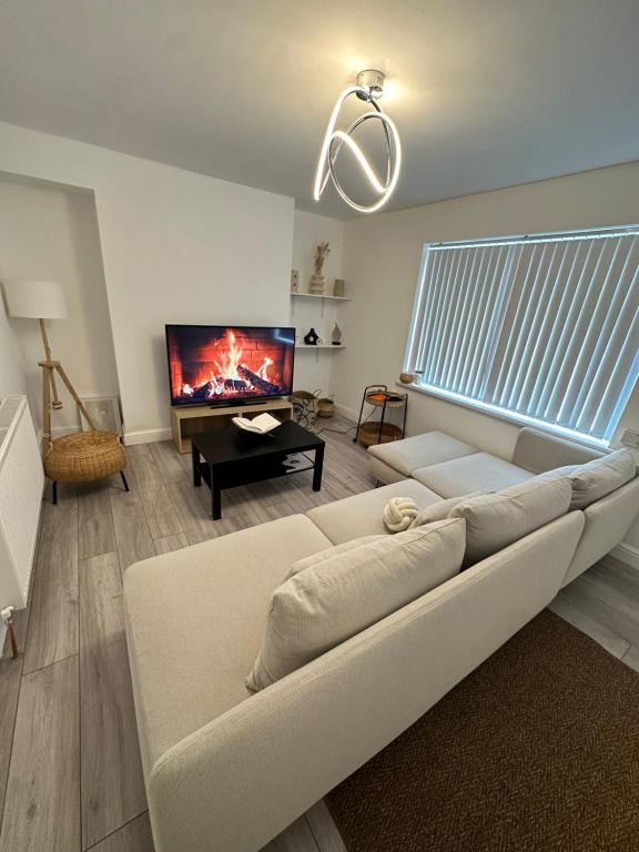 een woonkamer met een witte bank en een tv bij The Maison- Cozy home stay in Nottingham