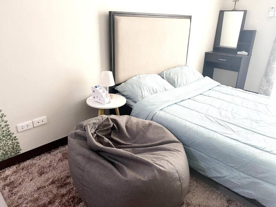 a bedroom with a bed with a round ottoman and a table at Condo Stay at Saekyung Looc in Lo-oc