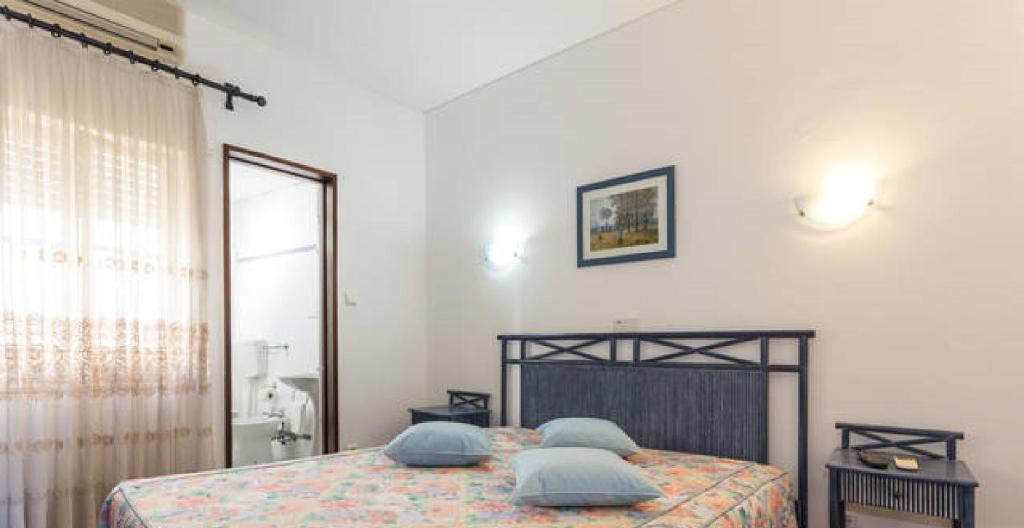 Un dormitorio con una cama con almohadas azules. en Residencial Miramar, en Quarteira