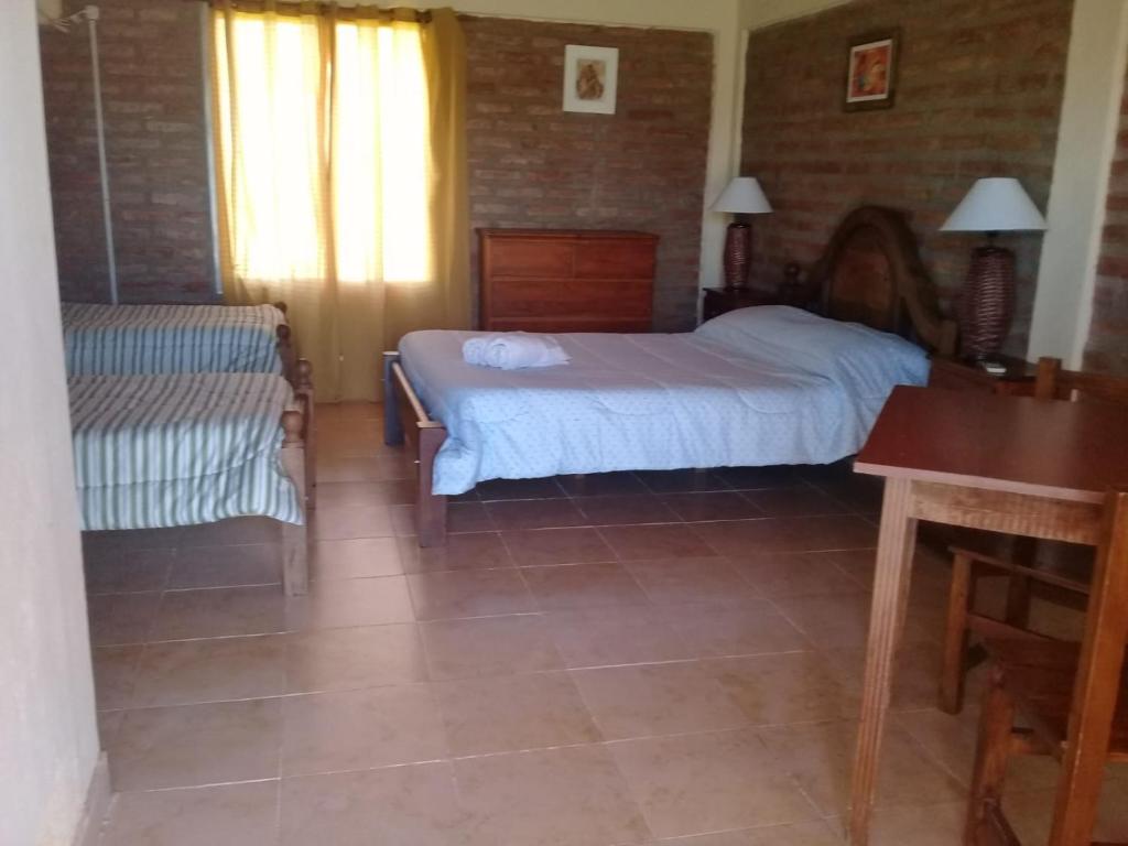 a bedroom with a bed and a bench and a table at HOTEL FINCA AMANCAY in Villa Unión