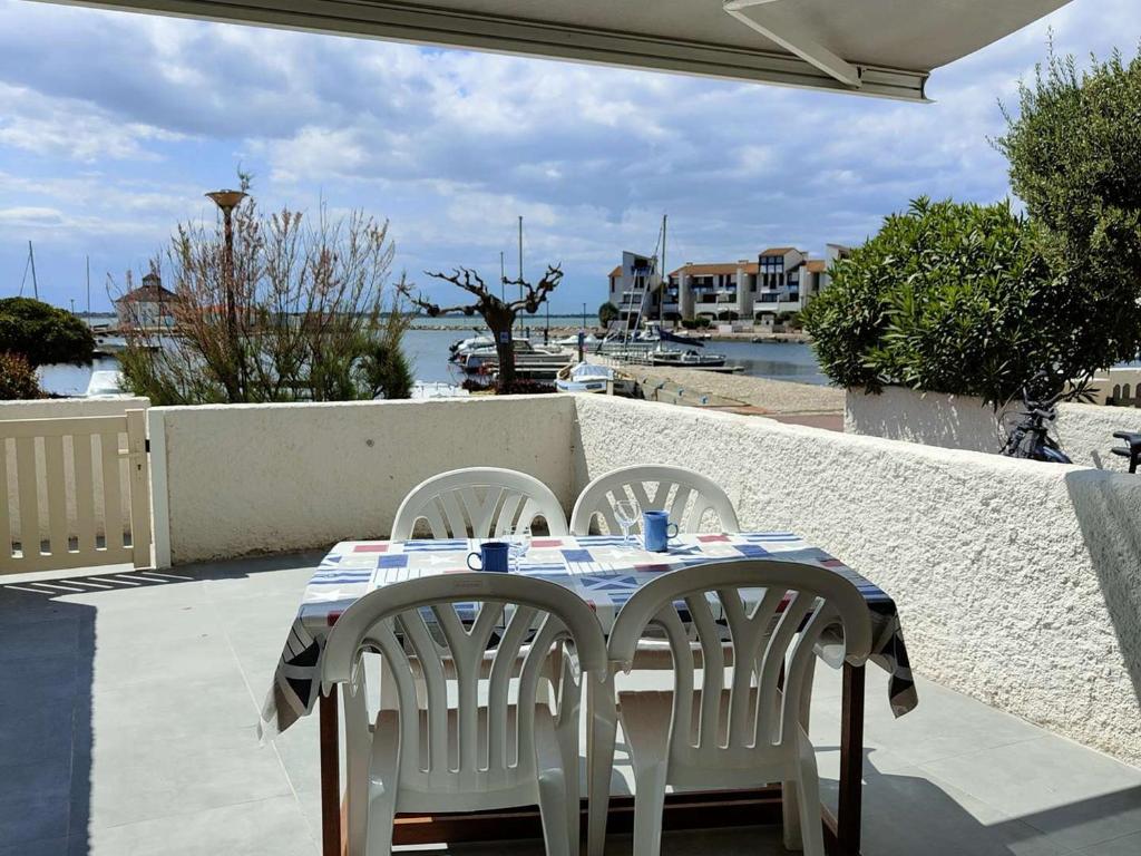 - une table et des chaises sur une terrasse avec vue sur l'eau dans l'établissement T2 avec Terrasse, Vue Port, Parking Privé, Espace Aquatique, et Plus - 4 Couchages - FR-1-195-99, au Barcarès