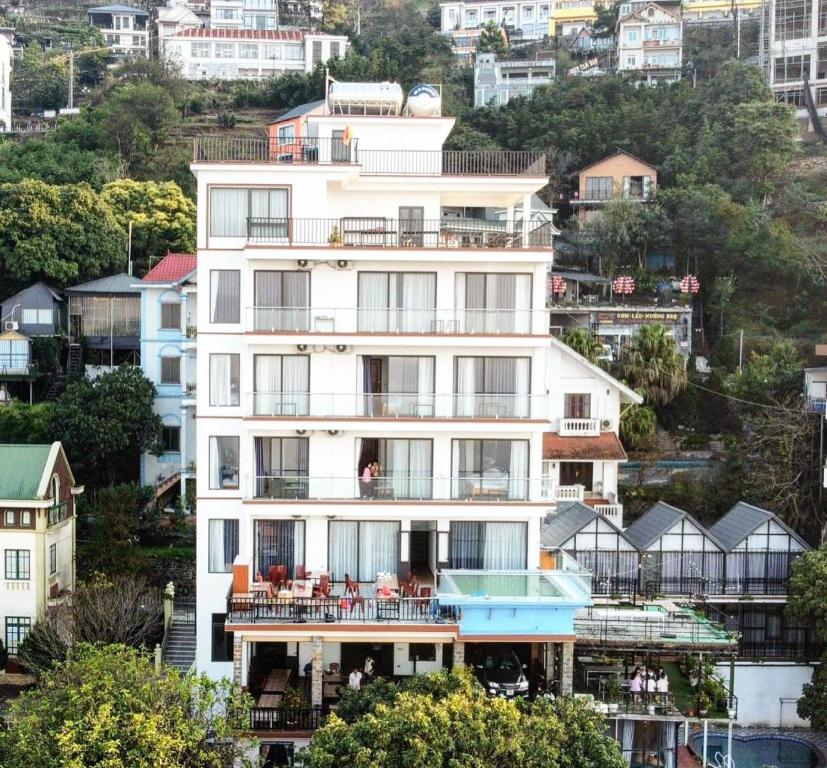 un gran edificio blanco en una colina con casas en Daisy Hotel Tam Dao en Tam Ðảo