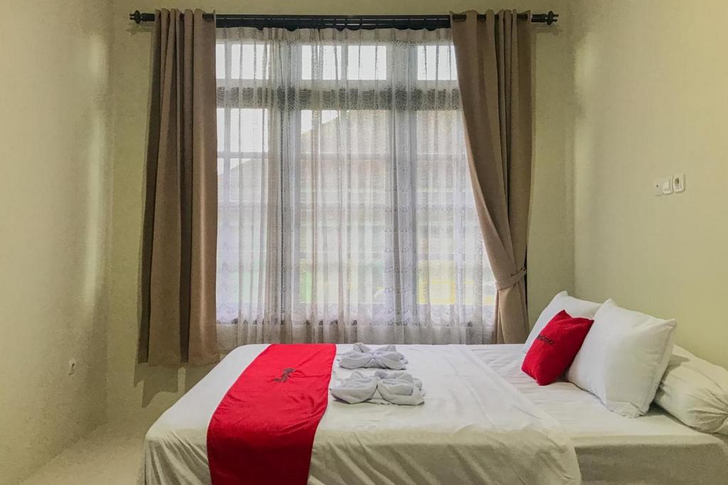 a bedroom with a bed with a large window at RedDoorz Syariah near Stasiun Madiun 2 in Madiun