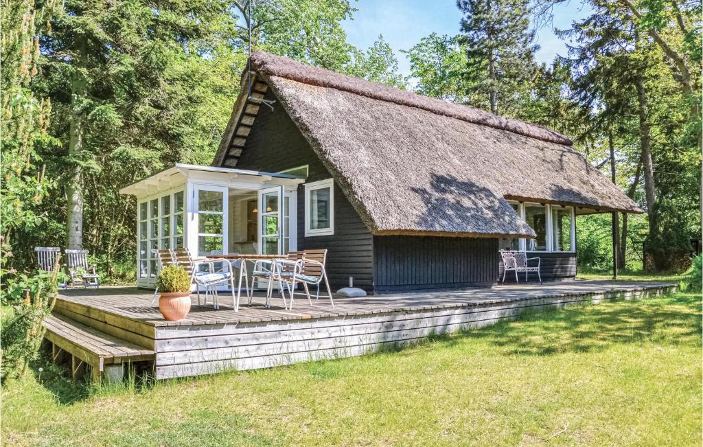 a small cottage with a thatched roof and a deck at Holiday Home Stængestykket in Udsholt Sand