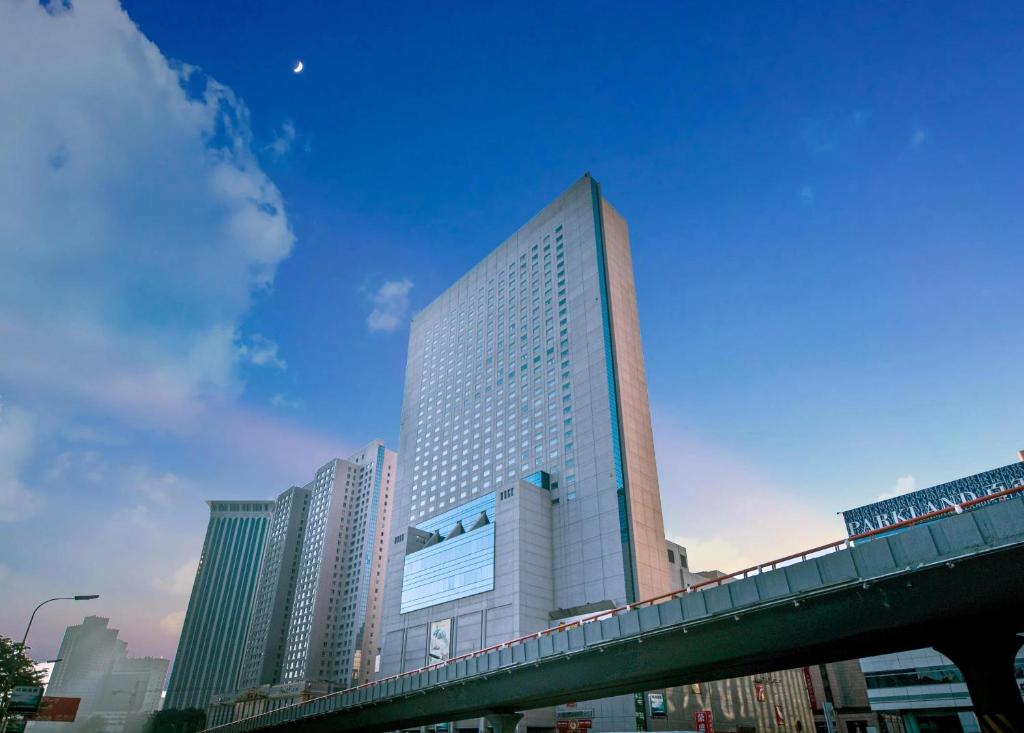 un edificio alto con un puente delante de él en Ruishi Hotel Dalian, en Dalian