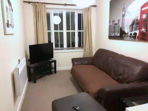 un salon avec un canapé brun et une télévision dans l'établissement Centralized Complete 3 BR Flat at Newcastle-Under-Lyme with a View-Free Parking, à Newcastle-under-Lyme
