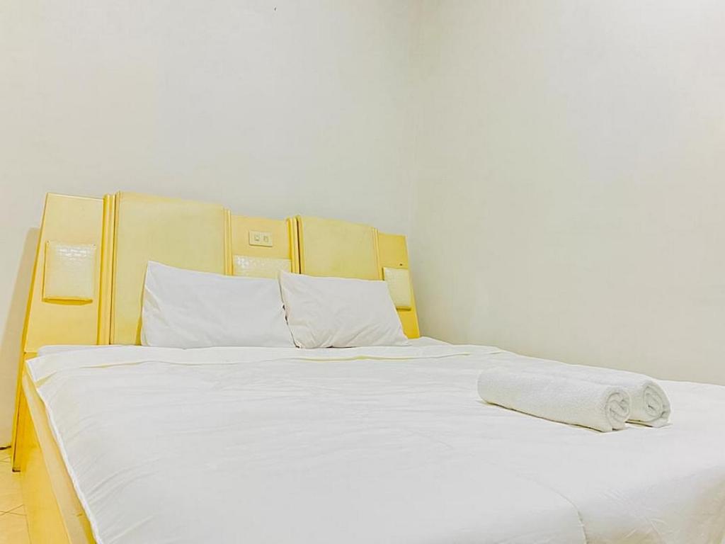 uma grande cama branca com lençóis e almofadas brancos em Monalisa Homestay Mitra RedDoorz em Surabaya