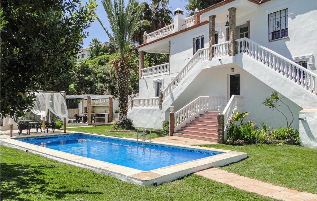 a villa with a swimming pool in front of a house at 4 Bedroom Gorgeous Home In Frigiliana in Nerja